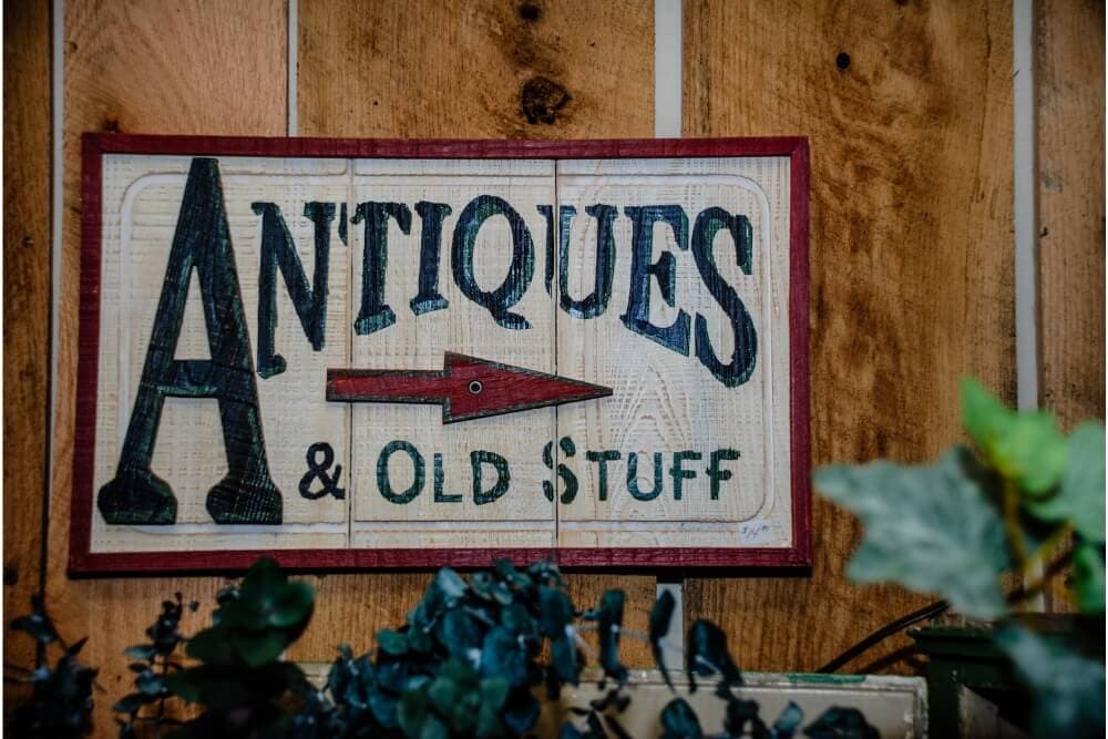 A wooden sign that reads "Antiques & Old Stuff" with an arrow pointing to the right.